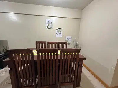 a dining room with a wooden table and chairs at Homey Staycation in Taguig in Manila