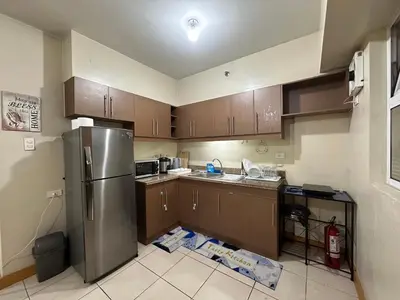 a kitchen with wooden cabinets and a stainless steel refrigerator at Homey Staycation in Taguig in Manila