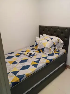 a bed with a blue and yellow quilt and pillows at Condo next door in Manila