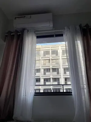 a window with a white curtain and a building at Pasay Condo near MOA, NAIA, CBD and Casinos in Manila