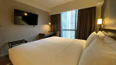 a hotel room with a large white bed and a window at Hotel Apartment Suite near Makati in Manila