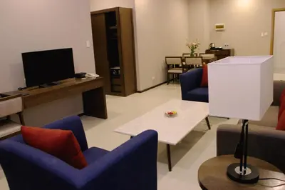 a living room with chairs and a tv and a table at Golden Phoenix Hotel - Manila in Manila