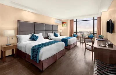a hotel room with two beds and a balcony at Golden Phoenix Hotel - Manila in Manila