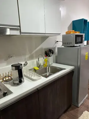 a kitchen with a sink and a refrigerator at Affordable Ayala Makati 1BR Condo in Manila