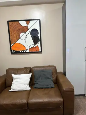 a brown couch in a living room with a painting at King-size Bed Makati Condo in Manila