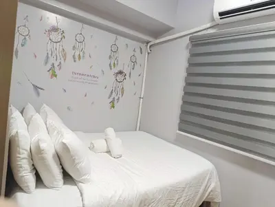 a bedroom with a bed with pillows and a wall with dreamcatchers at Kaths Place in Manila