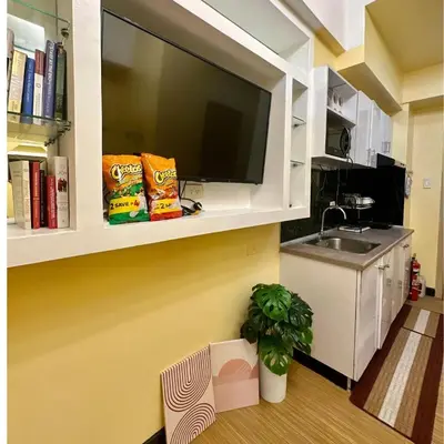 a kitchen with a sink and a tv on a wall at Cozy Stay Near BGC & Airport in Manila