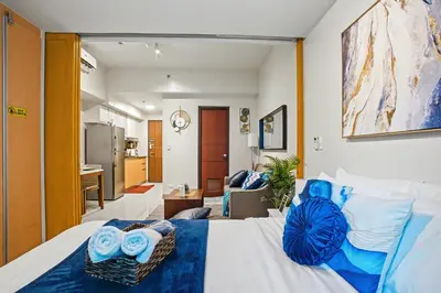 a bedroom with a bed and a living room at BGC High Rise, Uptown Mall Connector, 5G WiFi, Pool, Ste 15 in Manila