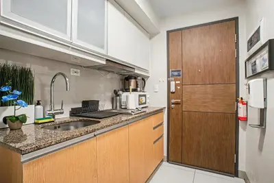 a kitchen with a sink and a wooden door at BGC High Rise, Uptown Mall Connector, 5G WiFi, Pool, Ste 15 in Manila