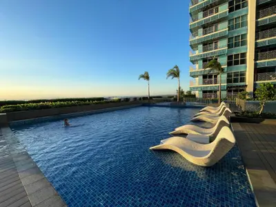 a swimming pool with white chairs in a building at Cozy 3BR near Airport and Okada in Manila