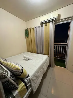 a bedroom with a bed and a window with a balcony at Macc staycation in Manila