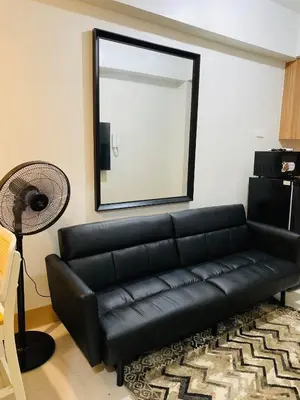 a black leather couch in a living room with a mirror at SMDC Shore 3 Residences in Manila