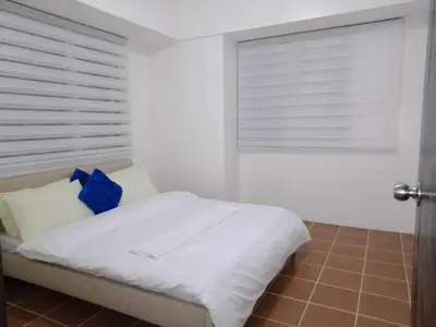 a bedroom with a bed with white sheets and blue pillows at 2BR Pioneer Woodland connected to Metro Rail Station SM Light,BONI Mandaluyong, Metro Manila,Philippines in Manila