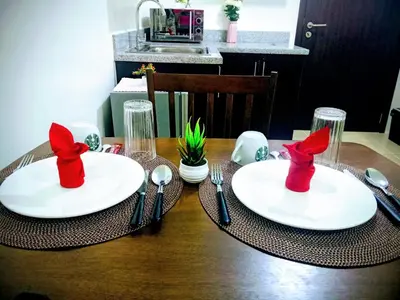 a table with two white plates with red napkins and silverware at 1BR Covent Garden South Tower University Belt- SM Sta Mesa, Metro Manila,Philippines in Manila