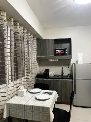 a kitchen with a table and a refrigerator at Faerydae Suites - Free Pool Access in Manila