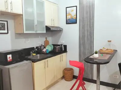 a small kitchen with a sink and a red chair at Perfect Location BGC - Mckinley in Manila