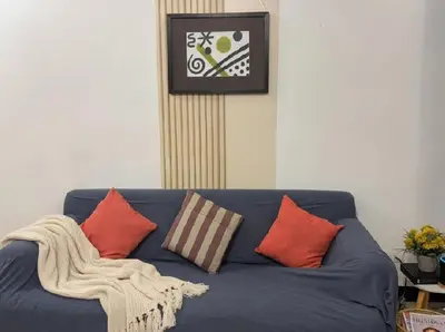 a blue couch with pillows and a clock on the wall at Perfect Location BGC - Mckinley in Manila