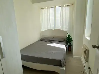 a bed in a small room with a window at Azure Staycation Condo Unit in Manila
