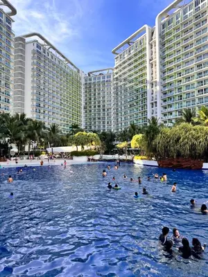a group of people swimming in the infinity pool at a resort at Azure Cozy Vibe Condo Unit in Manila