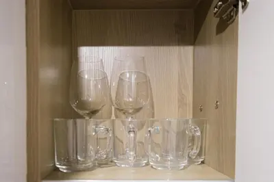 four empty wine glasses sitting on a shelf at Luxe 1BR with WiFi, Karaoke and Balcony Near SM Megamall in Manila