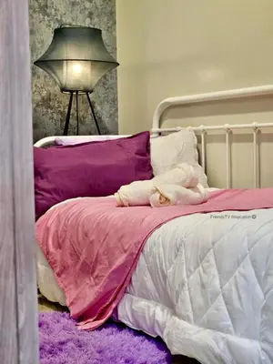 a bed with purple and white sheets and a lamp at FRIENDS TV Staycation in Manila