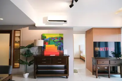 a living room with a desk and a painting at One Uptown Premium 2BR Suite in Manila
