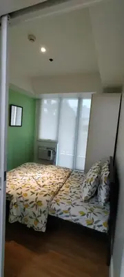 a bedroom with a bed with a comforter and windows at Azure Family Room Condo Unit in Manila