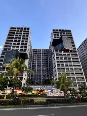 two tall buildings with palm trees in front of a street at La Chicka Staycation -1292 in Manila