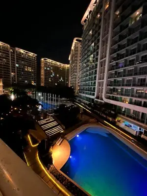 a view of a building with a swimming pool at night at Staycation in Azure Paranaque in Manila