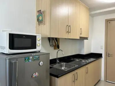 a kitchen with a sink and a microwave on top of a refrigerator at 1-Br Unit at Light Residences in Manila