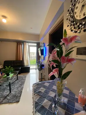 a living room with a table with a vase with flowers at JNL Condotel in Manila