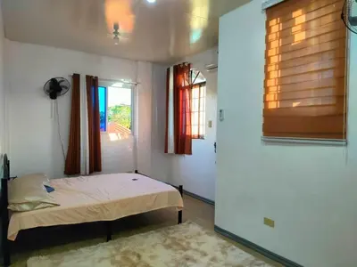 a small bedroom with a bed and a window at Simple, Spacious Home To Stay, 2Bedrooms 2 Toilet & Bath 1 car garage in Uldugan