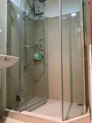 a shower with a glass door next to a sink at Tropical Sanctuary in Pasay City in Manila