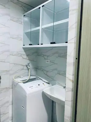 a bathroom with a glass cabinet above a toilet and a sink at Shore Residences C1 in Manila
