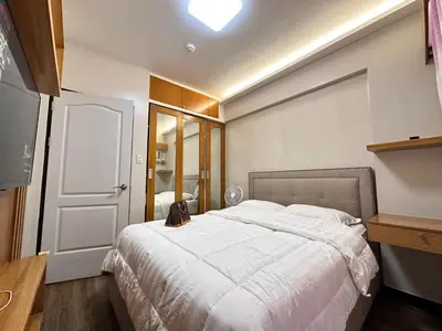 a bedroom with a large white bed and a door at The Cozysweet Homestay in Manila