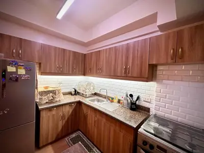 a kitchen with wooden cabinets and a stainless steel refrigerator at The Cozysweet Homestay in Manila