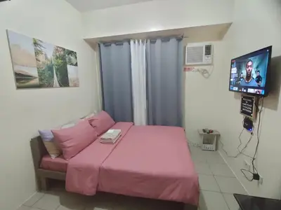 a bedroom with a pink bed and a tv at Gaby's Condotel in Manila