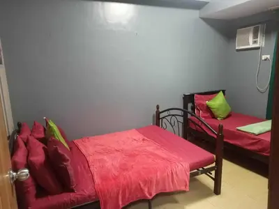 a bedroom with two beds with red sheets and green pillows at Family Budget Room in Manila