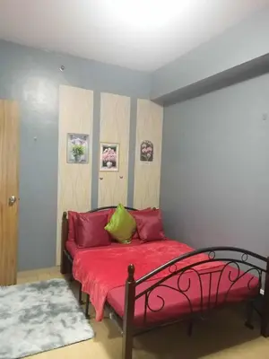 a bedroom with a bed with red sheets and green pillows at Family Budget Room in Manila