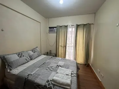 a small bedroom with a bed and a window at Staycation in Taguig in Manila