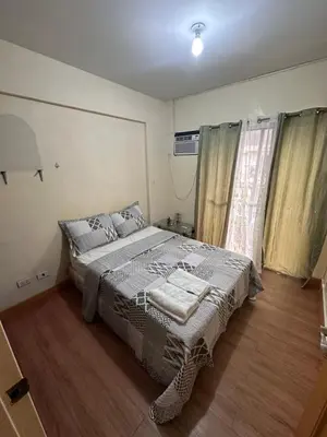 a bedroom with a bed and a window at Staycation in Taguig in Manila