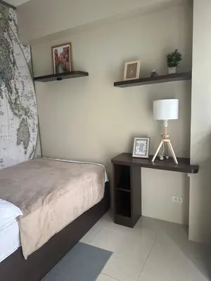 a bedroom with a bed and a table with a lamp at One Palm Tree by Melba STUDIO TYPE in Manila