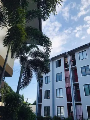 a white building with palm trees in front of it at Fiona Apartment in Manila