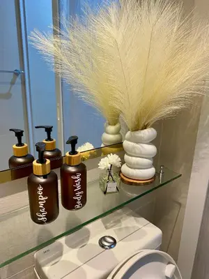 a bathroom with a shelf with four bottles of soap at Azure Staycation PH in Manila