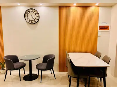 a waiting room with a table and chairs and a clock at Kate's Haven Jazz Residences Makati, Manila in Manila