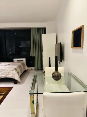 a living room with a couch and a glass table at Gramercy Residences Studio With Balcony City View in Manila