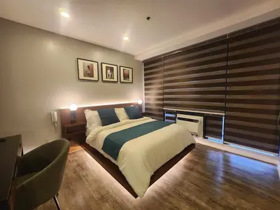 a bedroom with a bed and a chair in it at Prime Location Walk to Nightlife! The Gramercy in Manila
