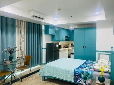 a bedroom with blue cabinets and a bed and a table at Sea View Condo in Manila