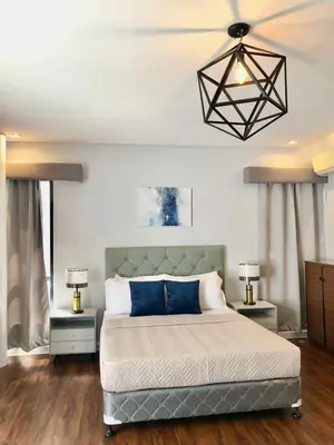 a bedroom with a large bed with blue pillows at Casa Bonifacio by JC in Manila