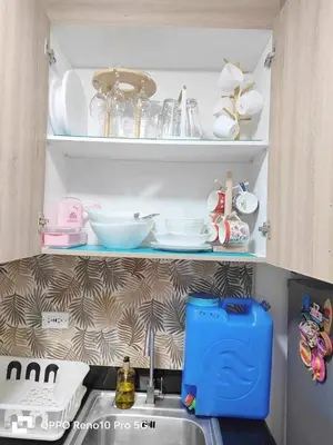 a kitchen sink with plates and dishes on a shelf at MOA Exquisite Suite Manila by JAO's Staycation in Manila